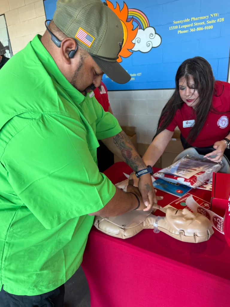 Volunteer trying CPR kits provided by TLC Complete Care at Hooks game